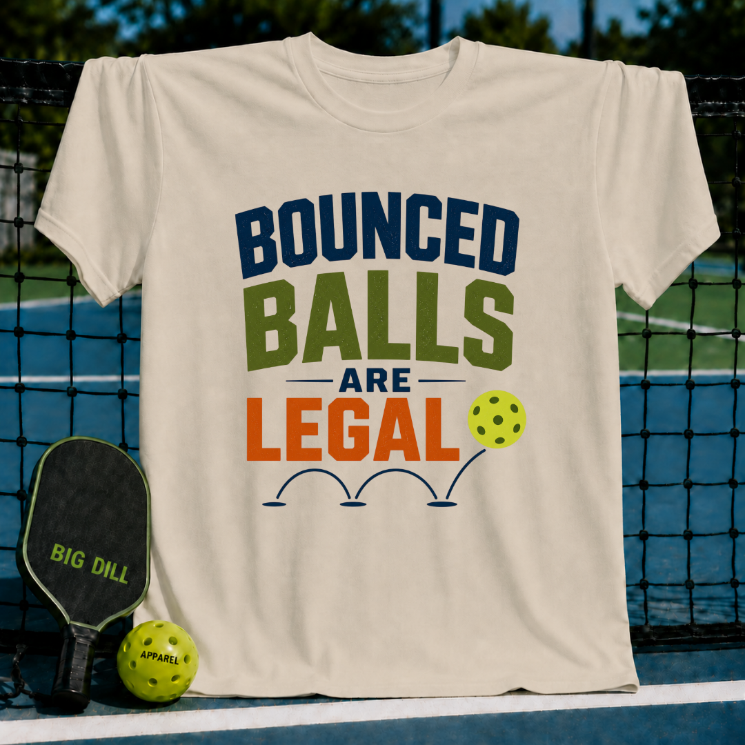 Beige unisex t-shirt featuring Bounced Balls Are Legal text with a pickleball graphic, displayed on a pickleball court.