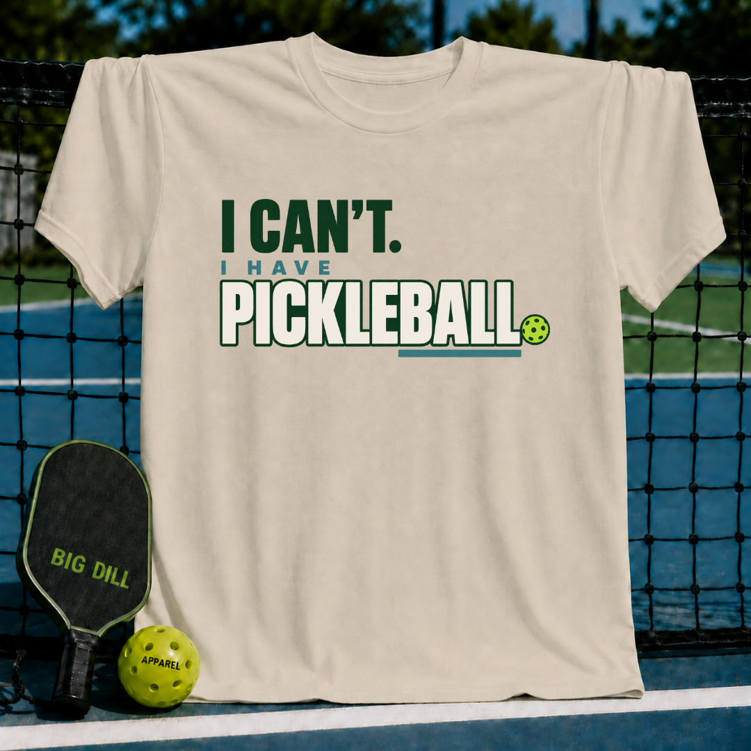 Beige crewneck t-shirt featuring green and blue I Can't I Have Pickleball text with a small pickleball graphic.