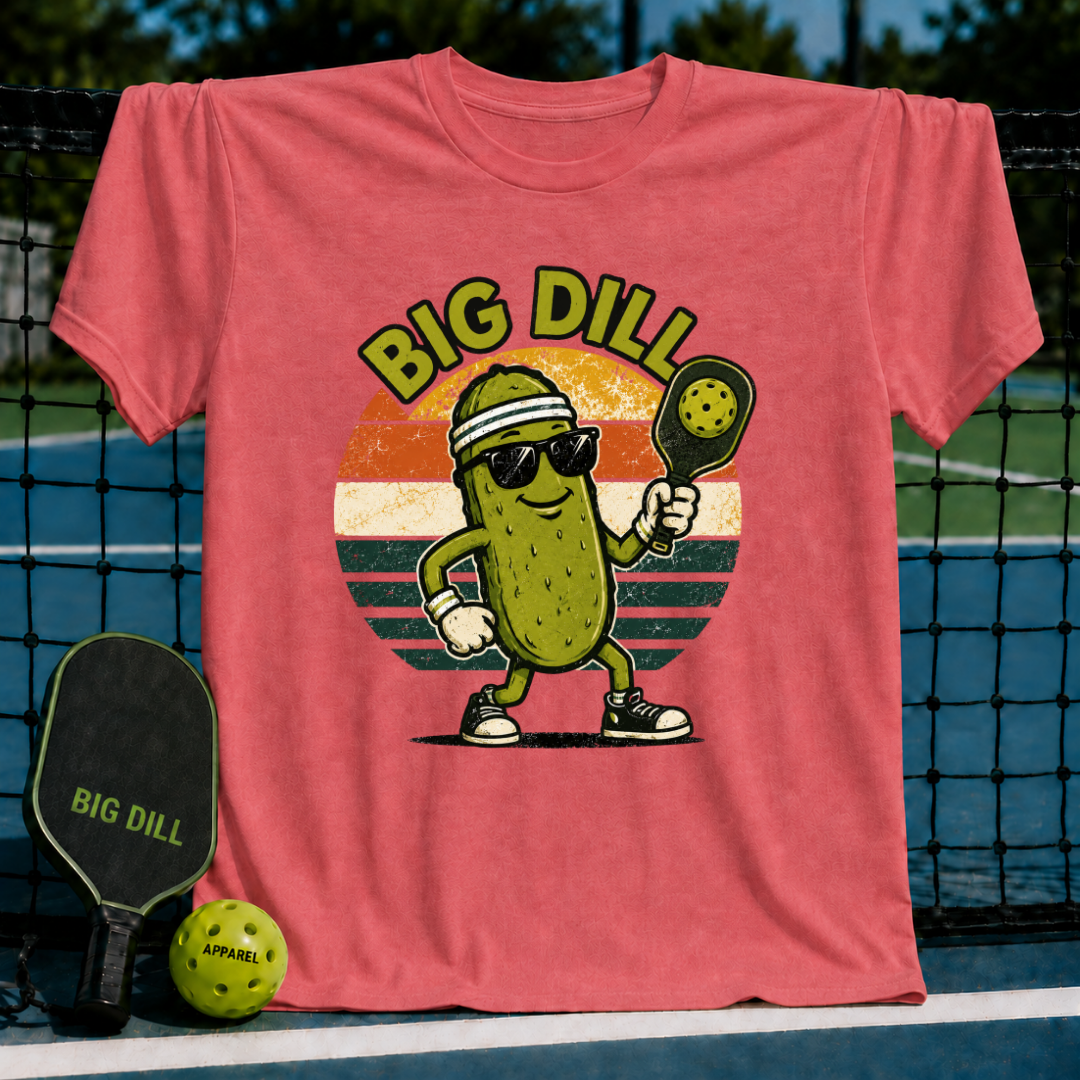 Coral unisex t-shirt featuring a retro pickleball-playing pickle character in sunglasses inside a sunset graphic.