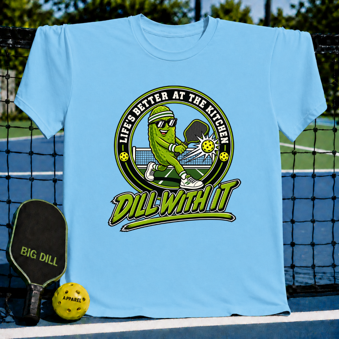 Light blue crew neck t-shirt featuring a pickleball-playing pickle graphic with the text Dill With It on a pickleball court.