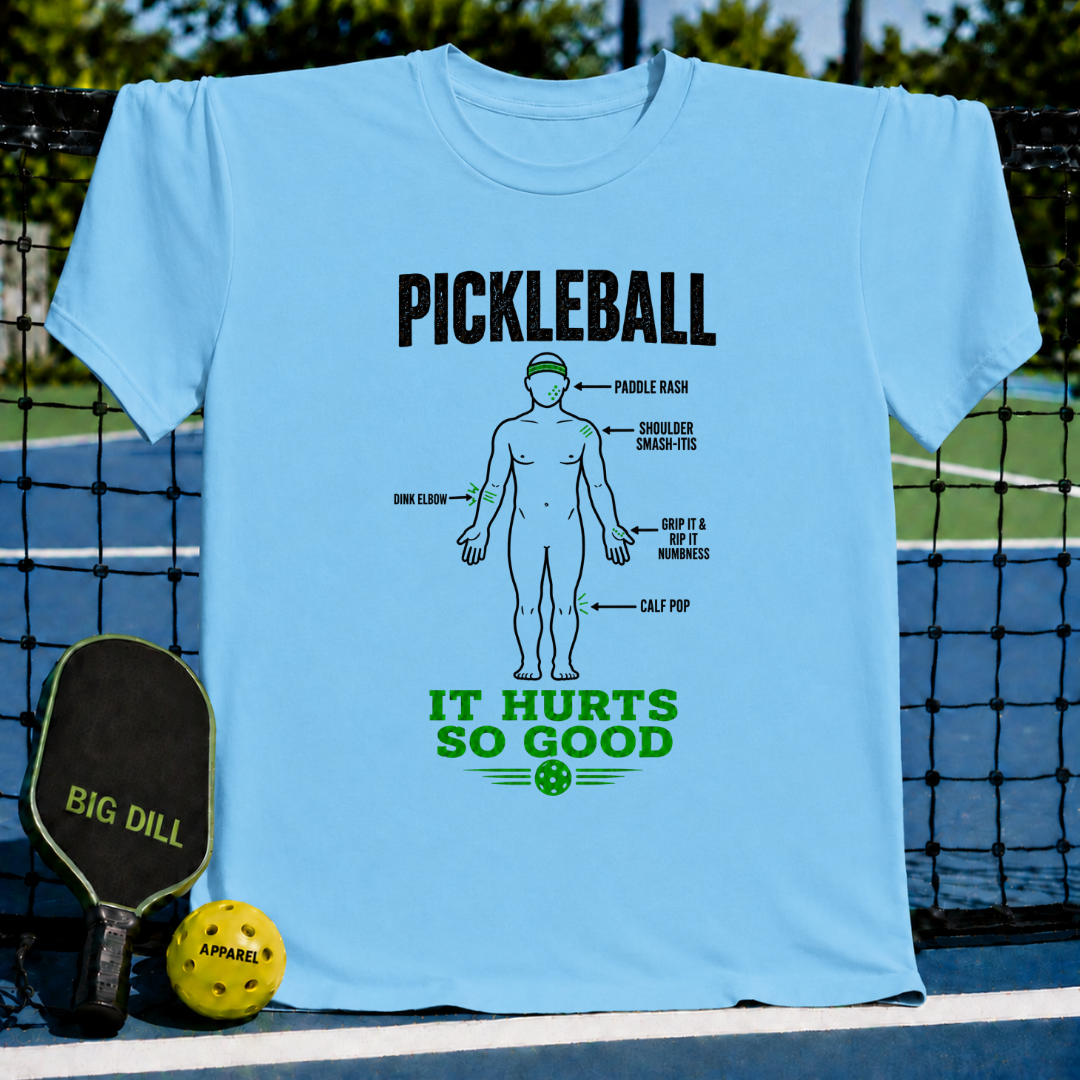 Light blue crew neck t-shirt featuring a humorous pickleball injury diagram graphic in black and green text.