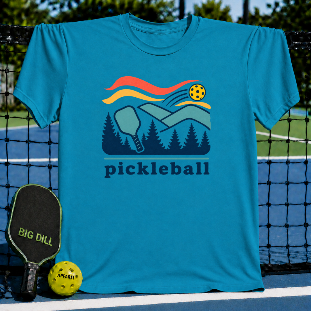 Blue crewneck t-shirt featuring a colorful pickleball, paddle, and forest graphic with the word pickleball printed below.