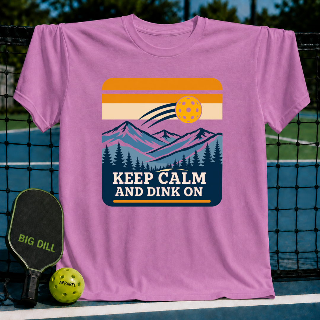 Pink T-shirt featuring a retro mountain landscape graphic with a pickleball and the text Keep Calm And Dink On.