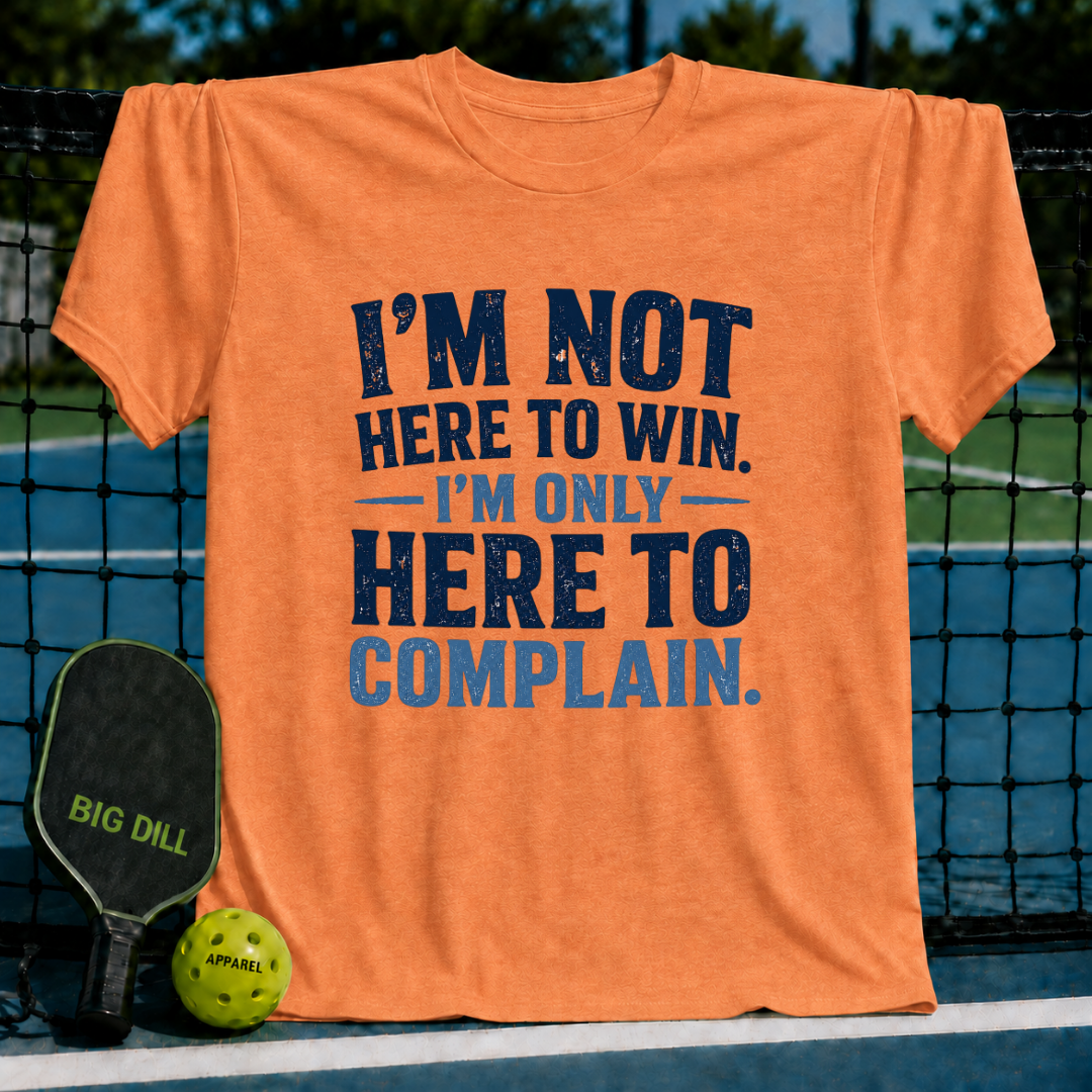 Orange unisex t-shirt featuring distressed navy blue text reading I'm Not Here To Win, I'm Only Here To Complain on a court.
