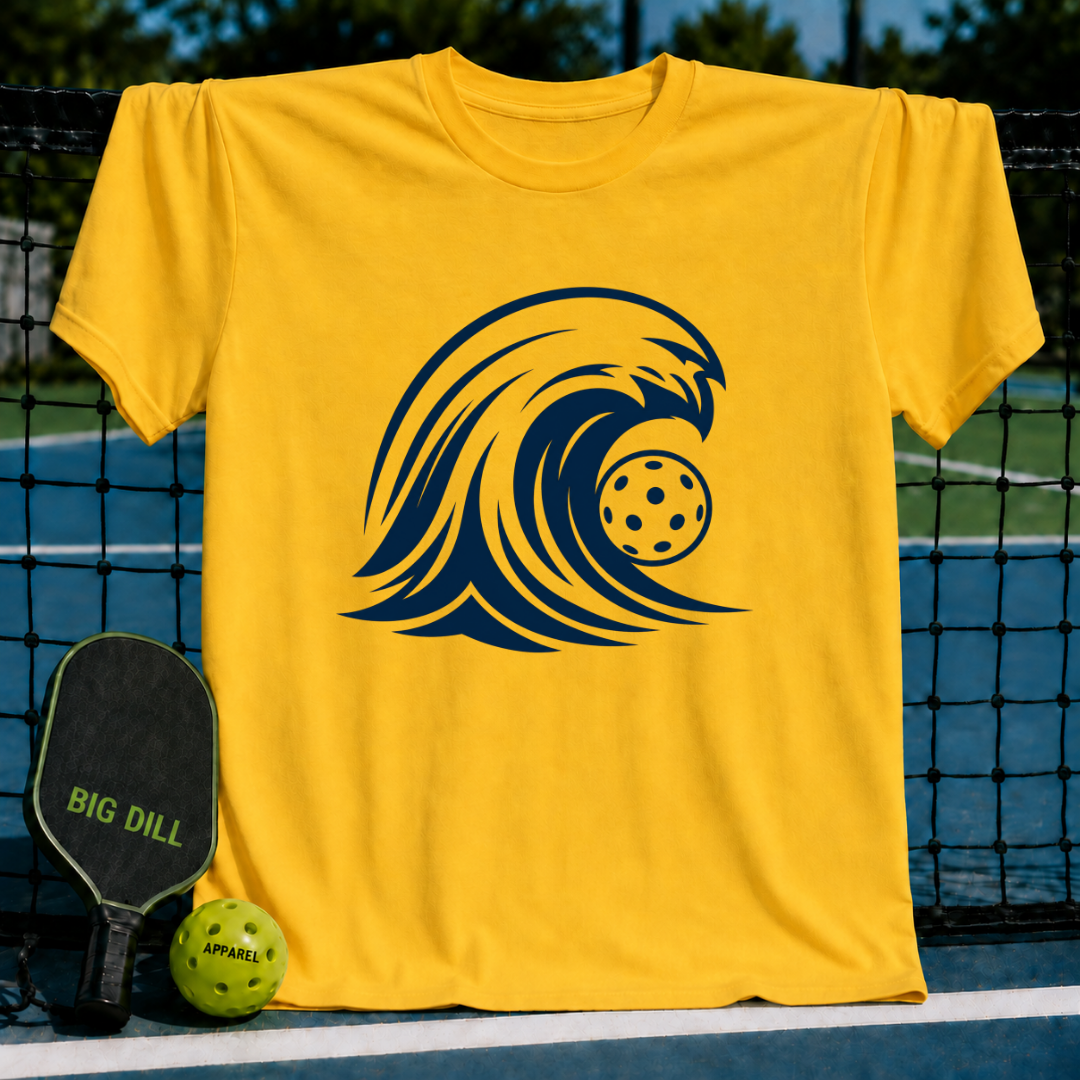 Bright yellow unisex t-shirt featuring a bold navy blue wave graphic with a pickleball, displayed on a pickleball court.