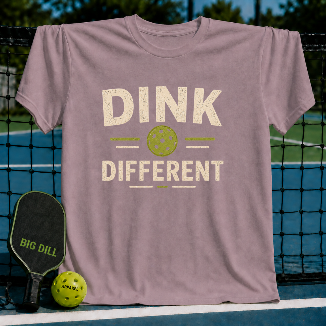 Mauve Dink Different pickleball t-shirt with a distressed cream and green graphic on a pickleball court background.