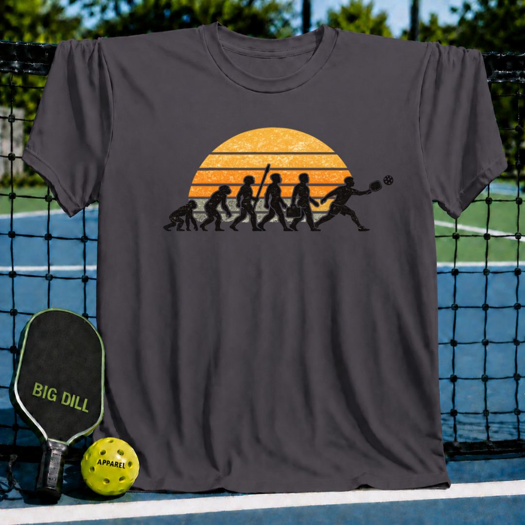 Charcoal grey t-shirt featuring a retro sunset evolution graphic of a man playing pickleball on a court background.