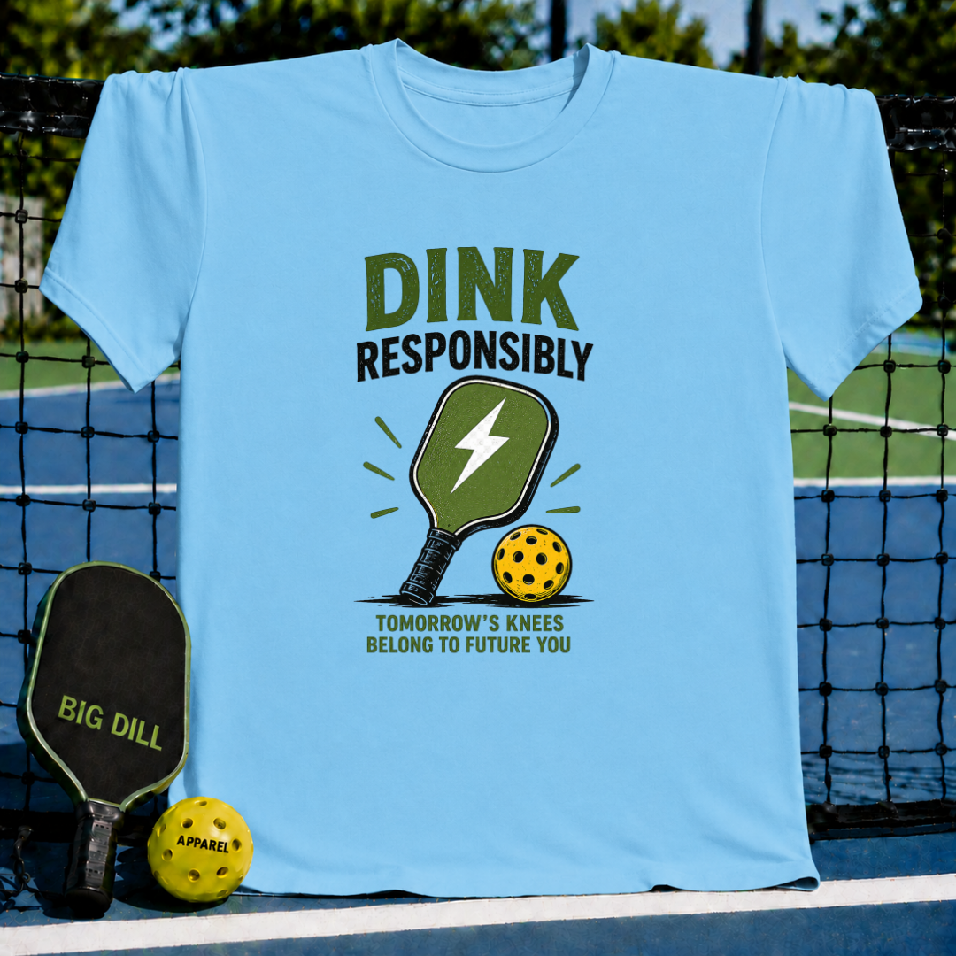 Light blue unisex t-shirt featuring a distressed Dink Responsibly graphic with a pickleball paddle and ball.
