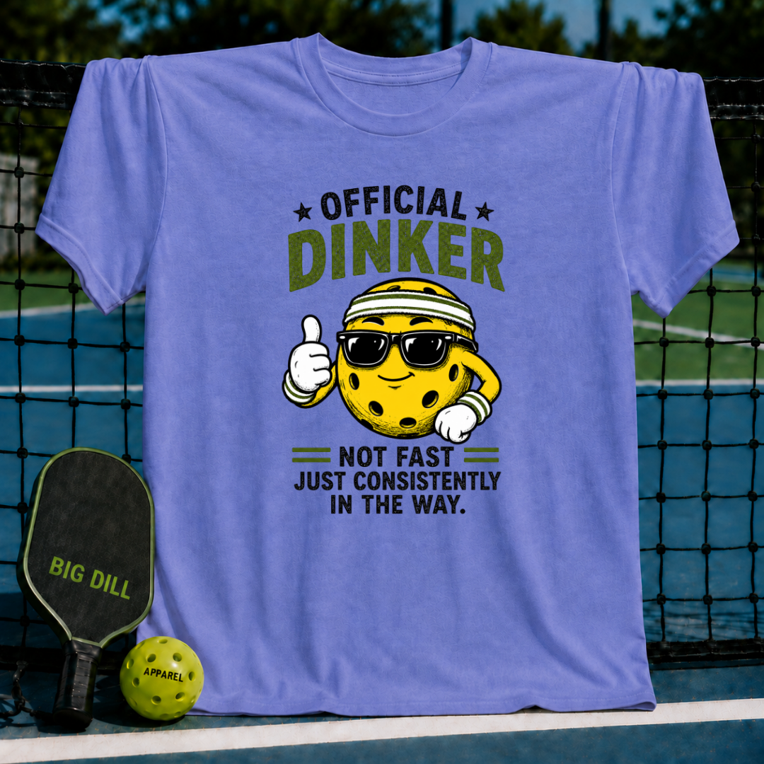 Periwinkle blue crewneck T-shirt featuring a cartoon pickleball character with sunglasses and the text Official Dinker.