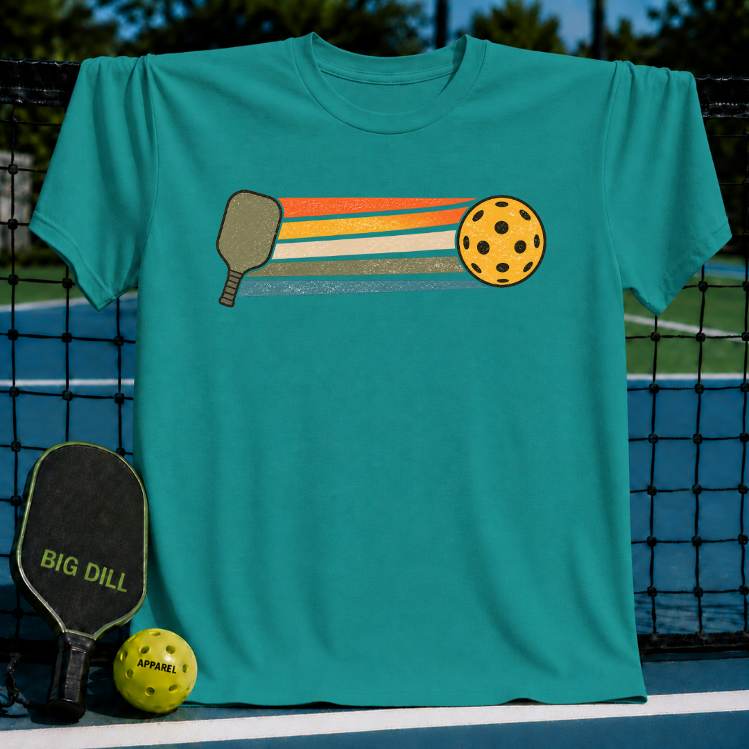 Teal unisex t-shirt featuring a retro graphic of a pickleball paddle and ball with colorful motion stripes.