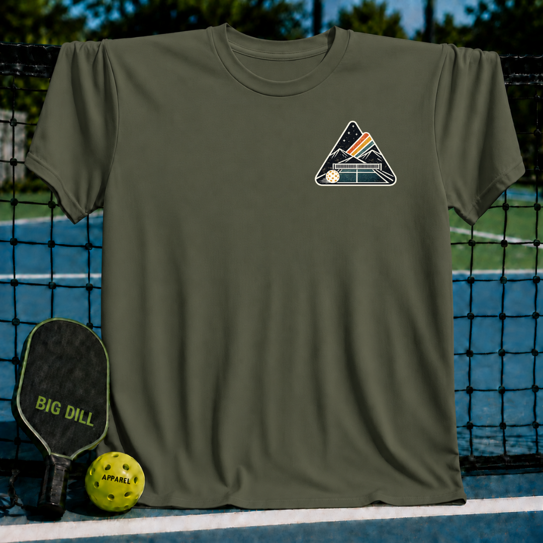 Olive green unisex t-shirt featuring a mountain and pickleball crest graphic on a pickleball court background.