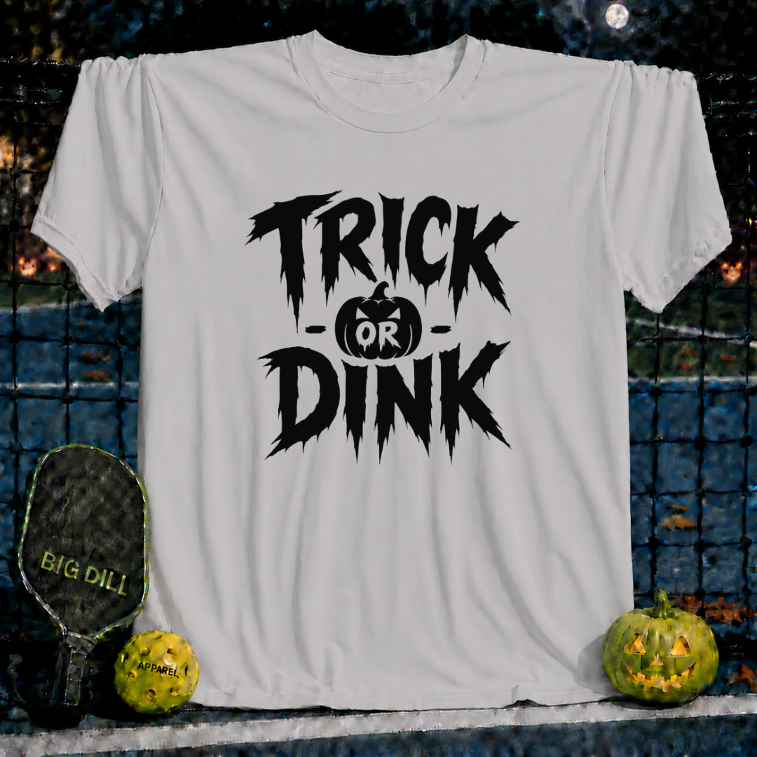 Ice grey unisex t-shirt featuring a spooky black Trick-or-Dink pumpkin graphic, displayed on a pickleball court background.