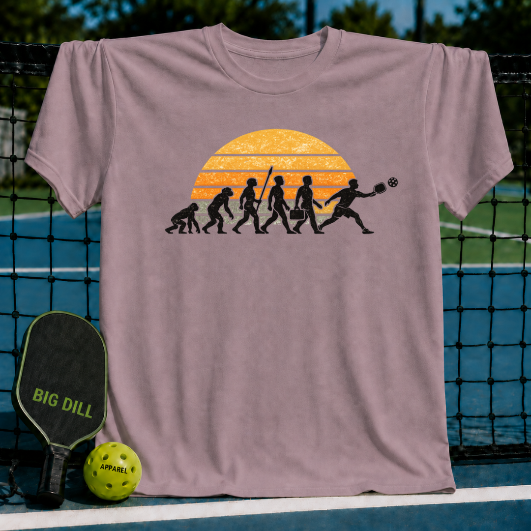 Mauve t-shirt featuring a retro sunset evolution graphic of a man playing pickleball, displayed on a court net.