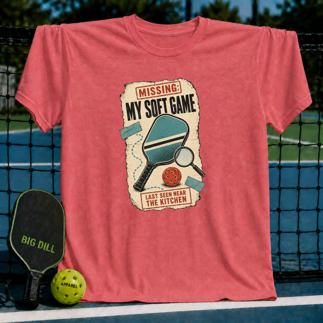 Coral red crewneck t-shirt featuring a vintage-style pickleball graphic with a paddle, ball, and magnifying glass.