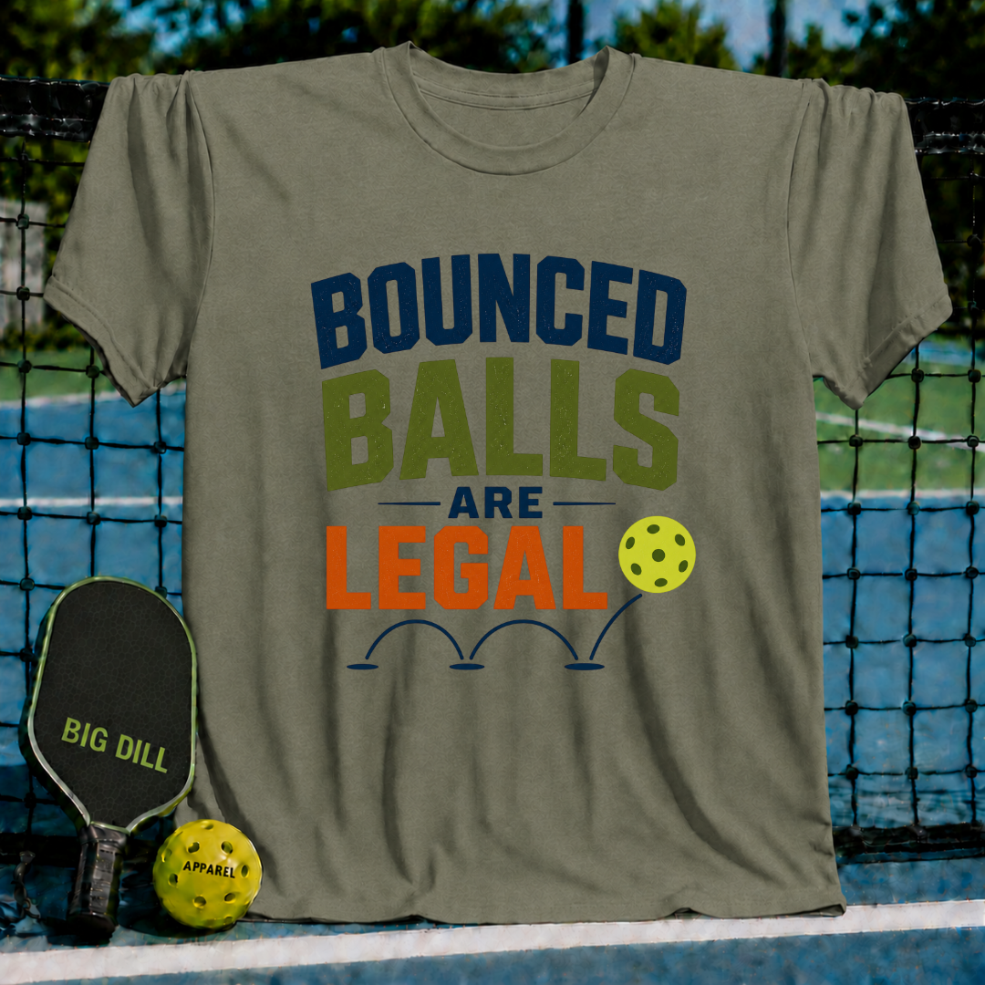Olive green unisex pickleball t-shirt with Bounced Balls Are Legal typography, displayed on a court with a paddle and ball.