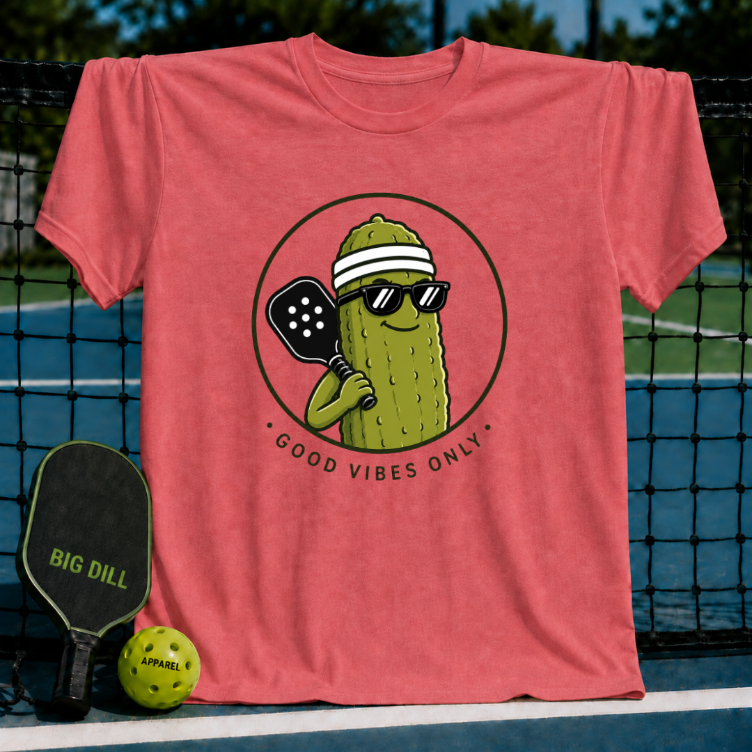 Coral unisex t-shirt featuring a circular graphic of a smiling pickle wearing sunglasses and a visor with a pickleball paddle.