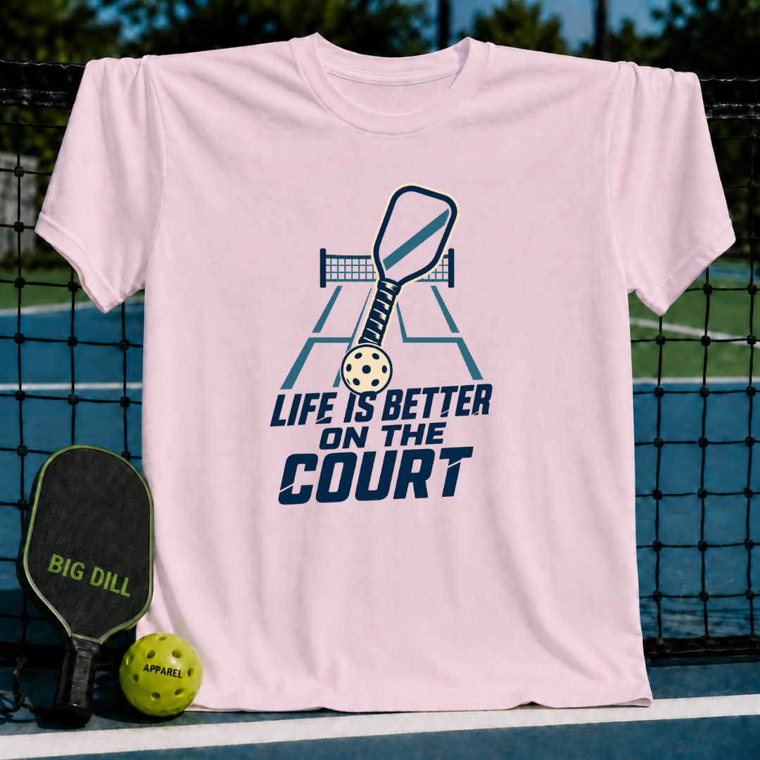 Light pink cotton t-shirt featuring a blue pickleball paddle and court graphic with the text Life is Better on the Court.