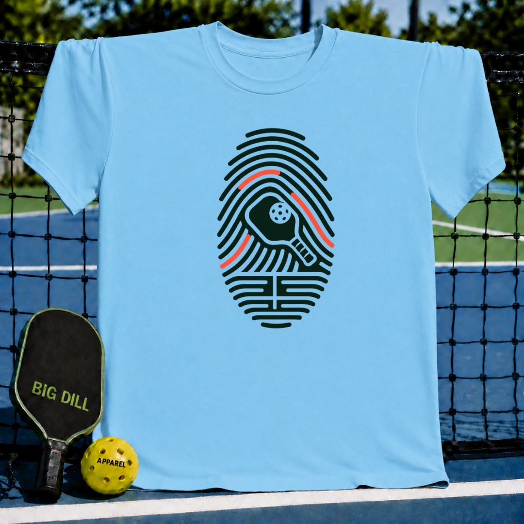 Light blue crew neck t-shirt featuring a dark green fingerprint graphic with a pickleball paddle and ball design.
