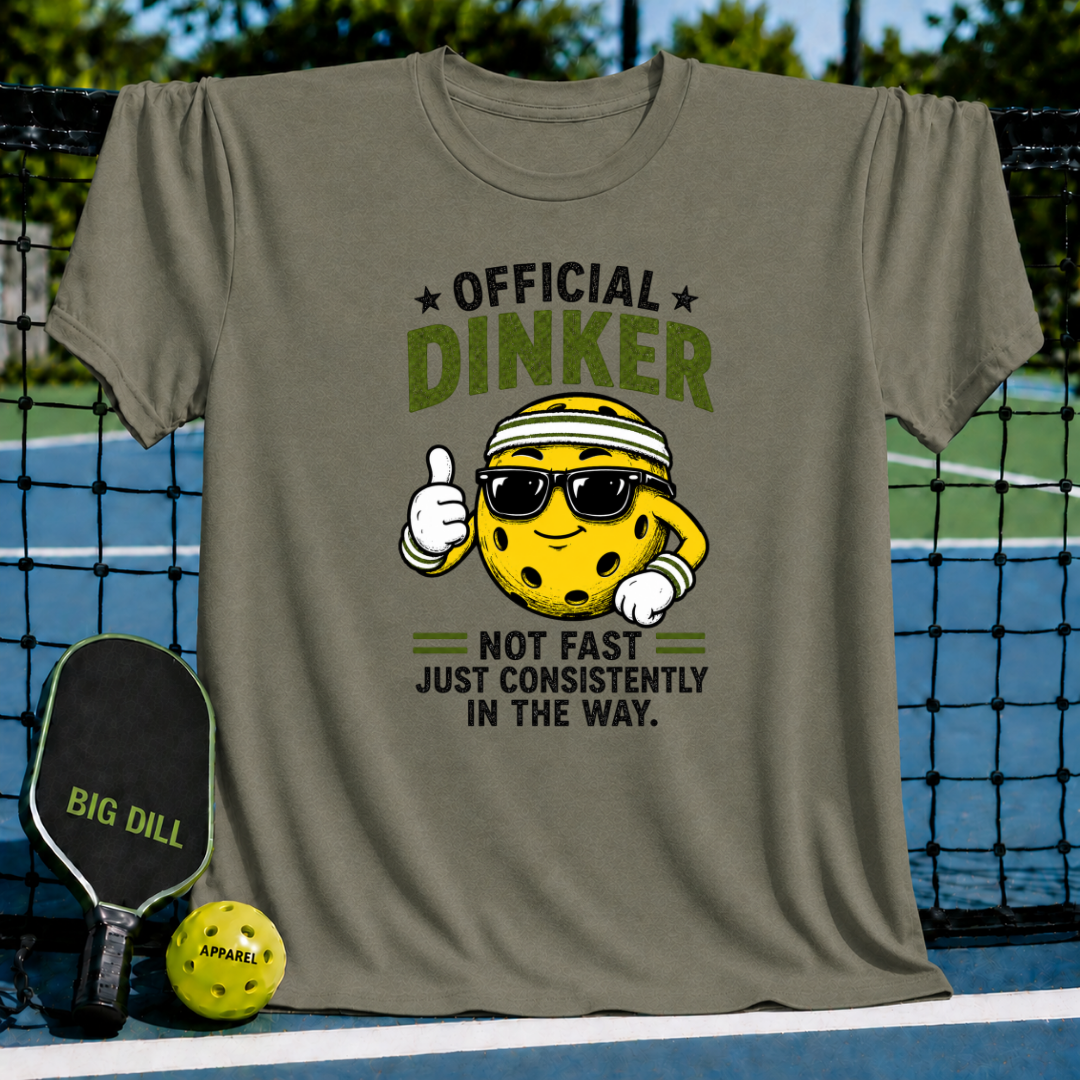 Olive green t-shirt featuring a cartoon pickleball character with sunglasses and the text Official Dinker on a court background.