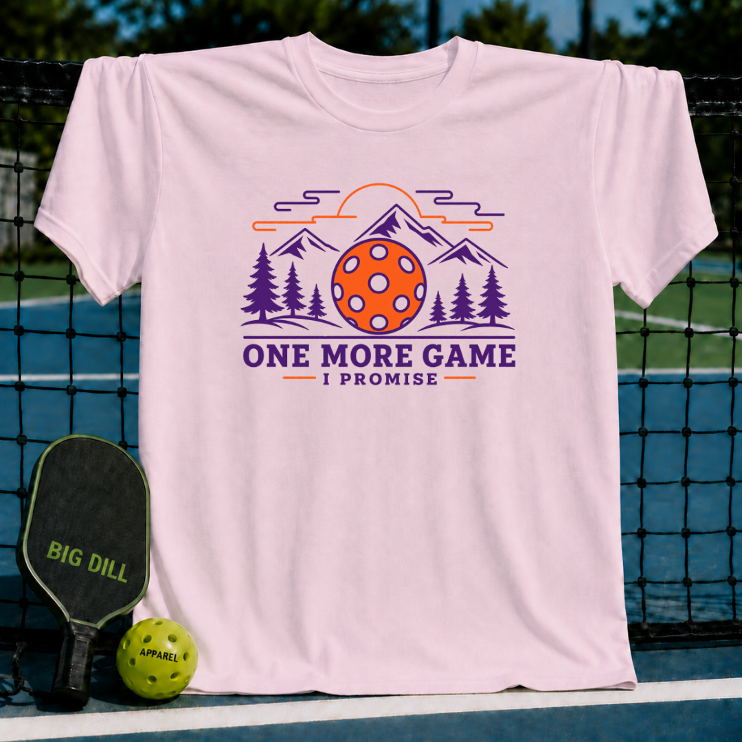 Light pink cotton t-shirt featuring a mountain, pine tree, and pickleball graphic with the text One More Game I Promise.