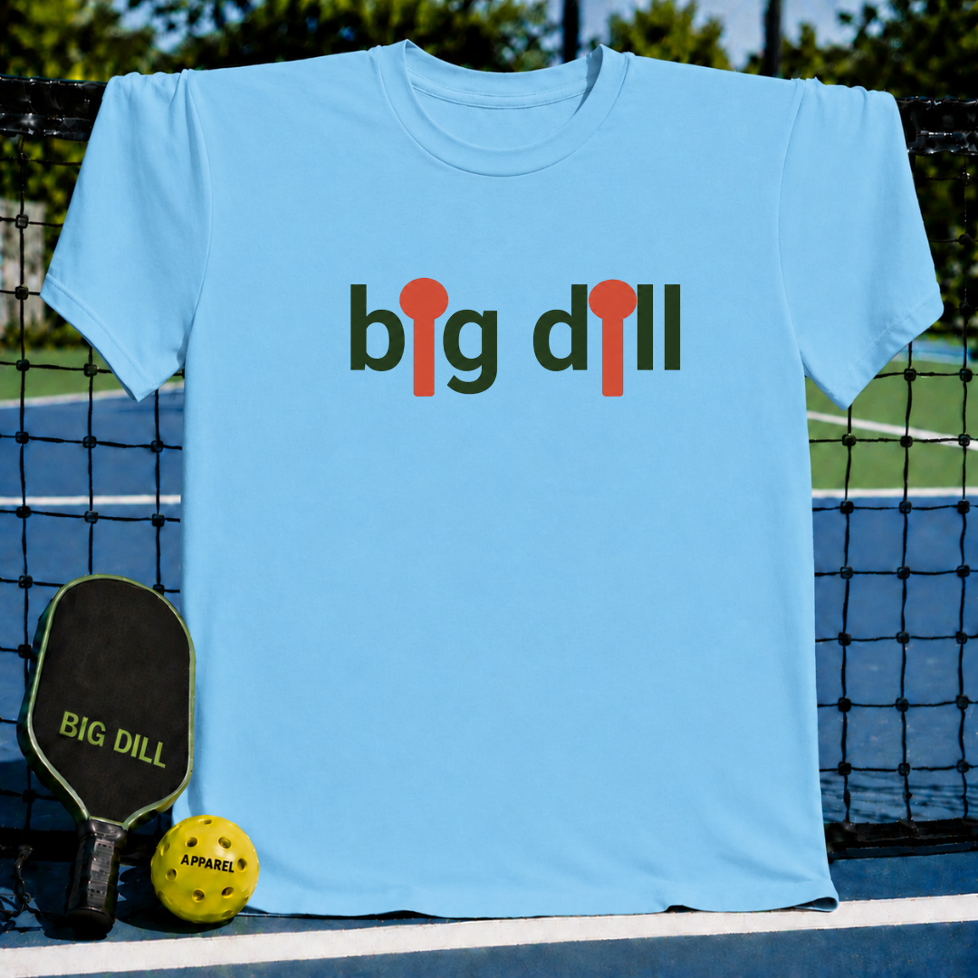 Light blue unisex t-shirt featuring a dark green and orange graphic with pickleball paddle icons replacing the letter I.
