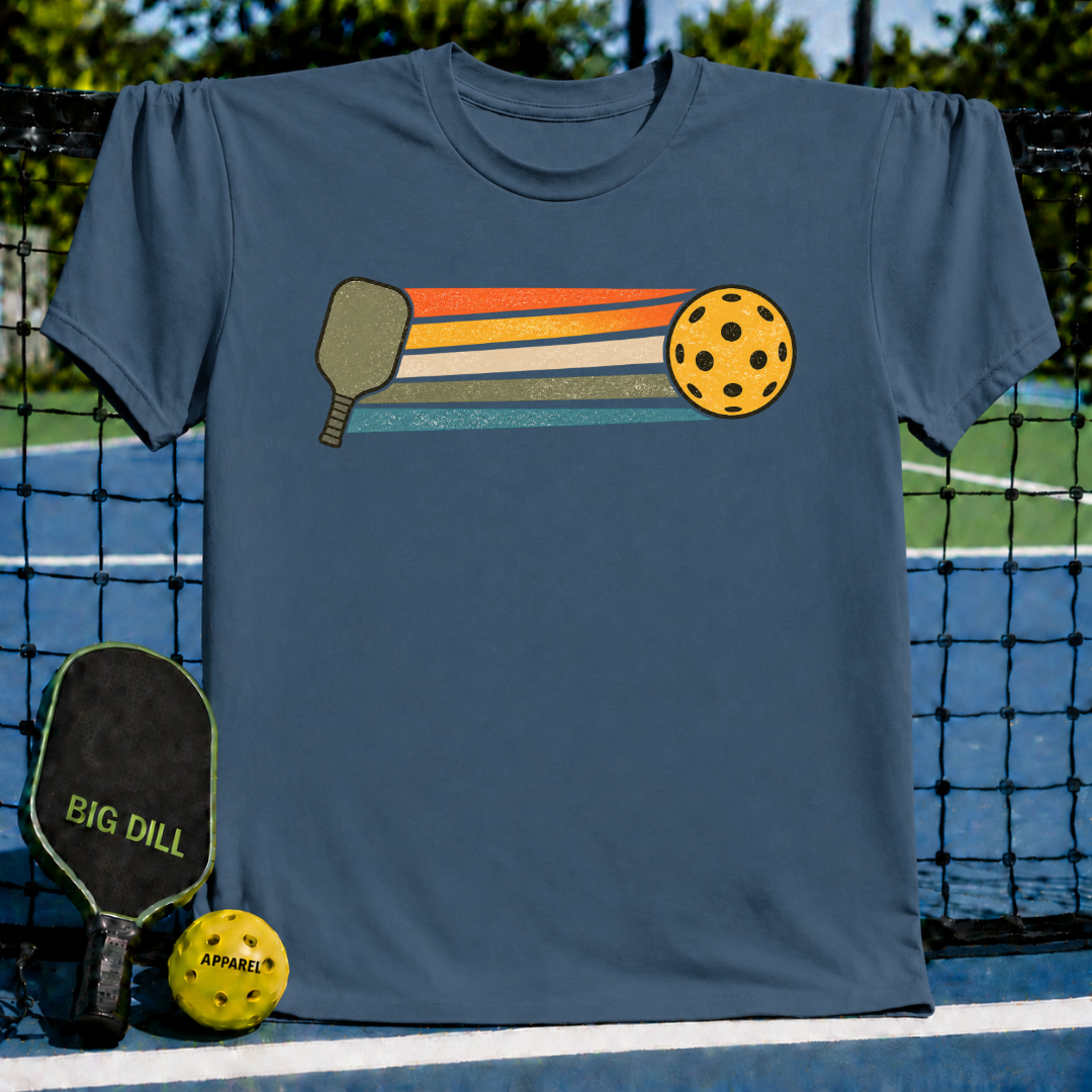 Blue unisex t-shirt featuring a retro graphic of a pickleball paddle, yellow ball, and colorful motion stripes.