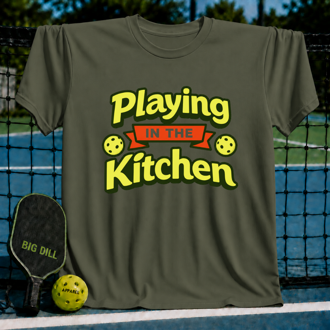 Olive green crewneck t-shirt featuring a yellow and orange Playing in the Kitchen pickleball graphic design.
