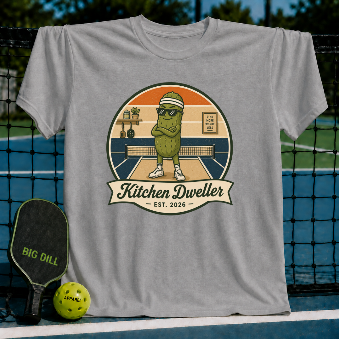Grey unisex t-shirt featuring a retro pickleball graphic of a pickle wearing sunglasses and a visor on a court.