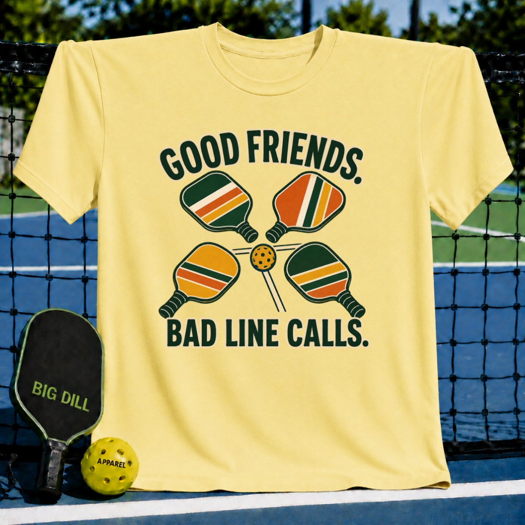 Pale yellow crew neck t-shirt featuring a retro pickleball graphic with paddles, a ball, and the text Good Friends Bad Line Calls.
