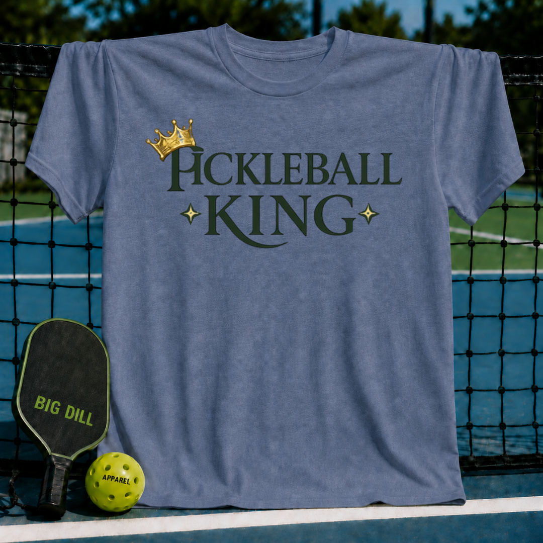 Blue-grey unisex t-shirt featuring Pickleball King text, a gold crown, and star accents, displayed on a pickleball court net.