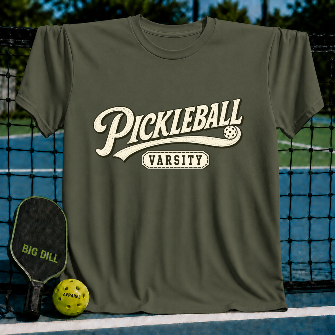 Olive green crew neck t-shirt with vintage-style white Pickleball Varsity graphic lettering on a court background.