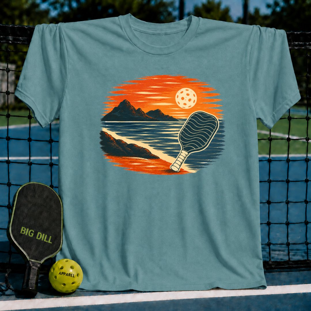 Teal unisex t-shirt featuring a vintage sunset landscape illustration with a pickleball paddle on a court background.
