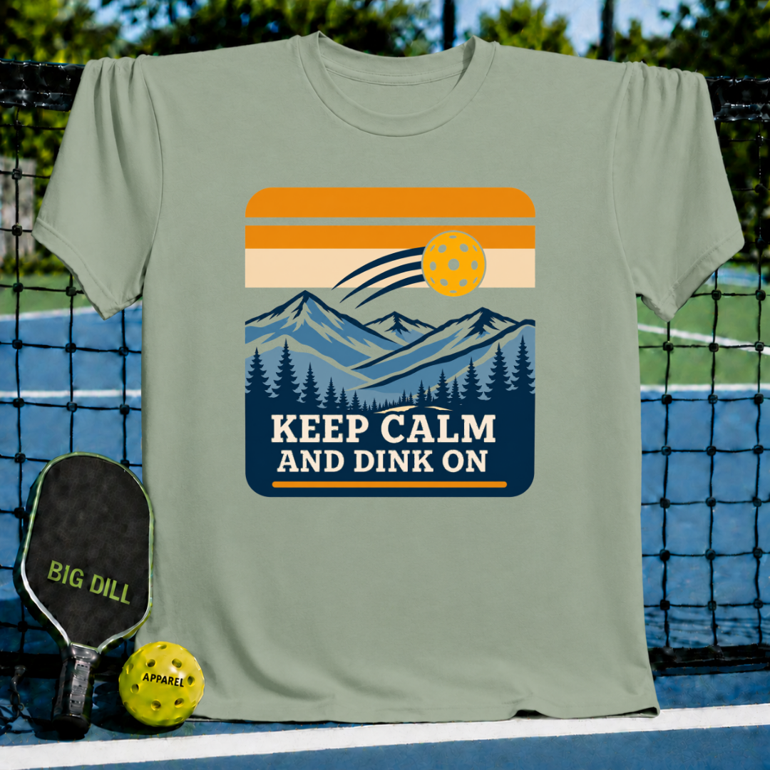 Sage green crewneck t-shirt featuring a retro mountain landscape graphic with a pickleball and Keep Calm And Dink On text.