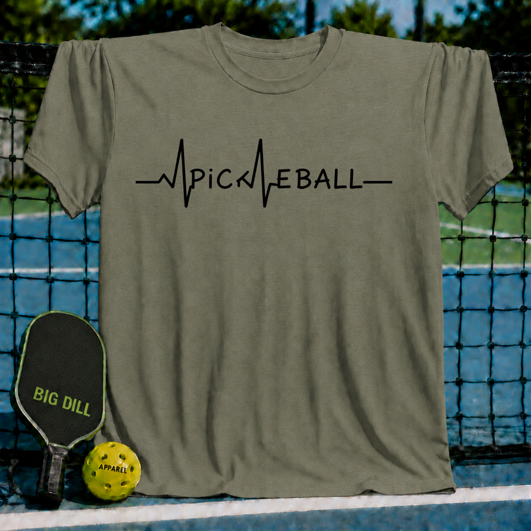 Olive green unisex t-shirt featuring a black EKG heartbeat line graphic that spells out PICKLEBALL, displayed on a court.