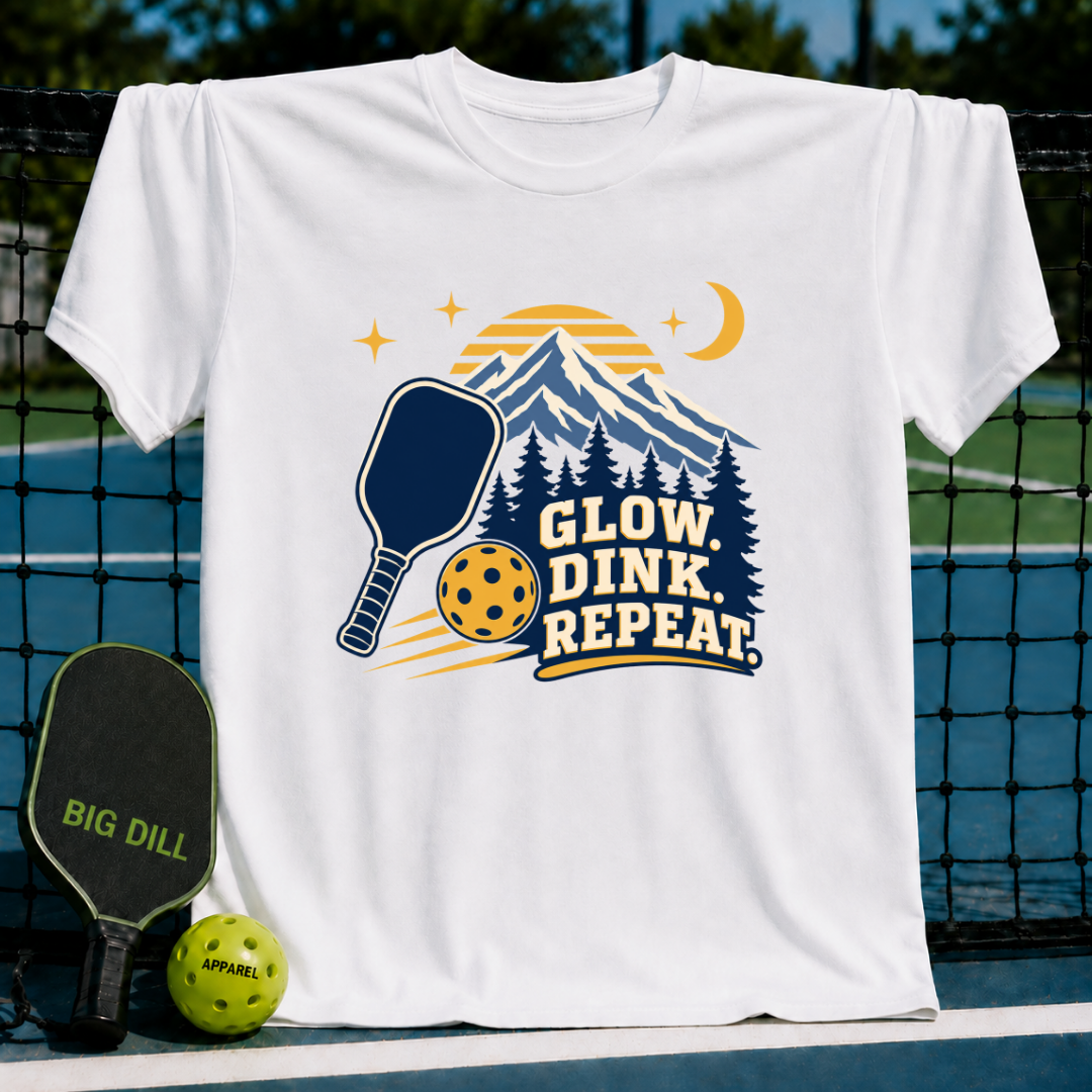 White cotton t-shirt featuring a mountain, pickleball paddle, and Glow Dink Repeat text graphic in navy and yellow.