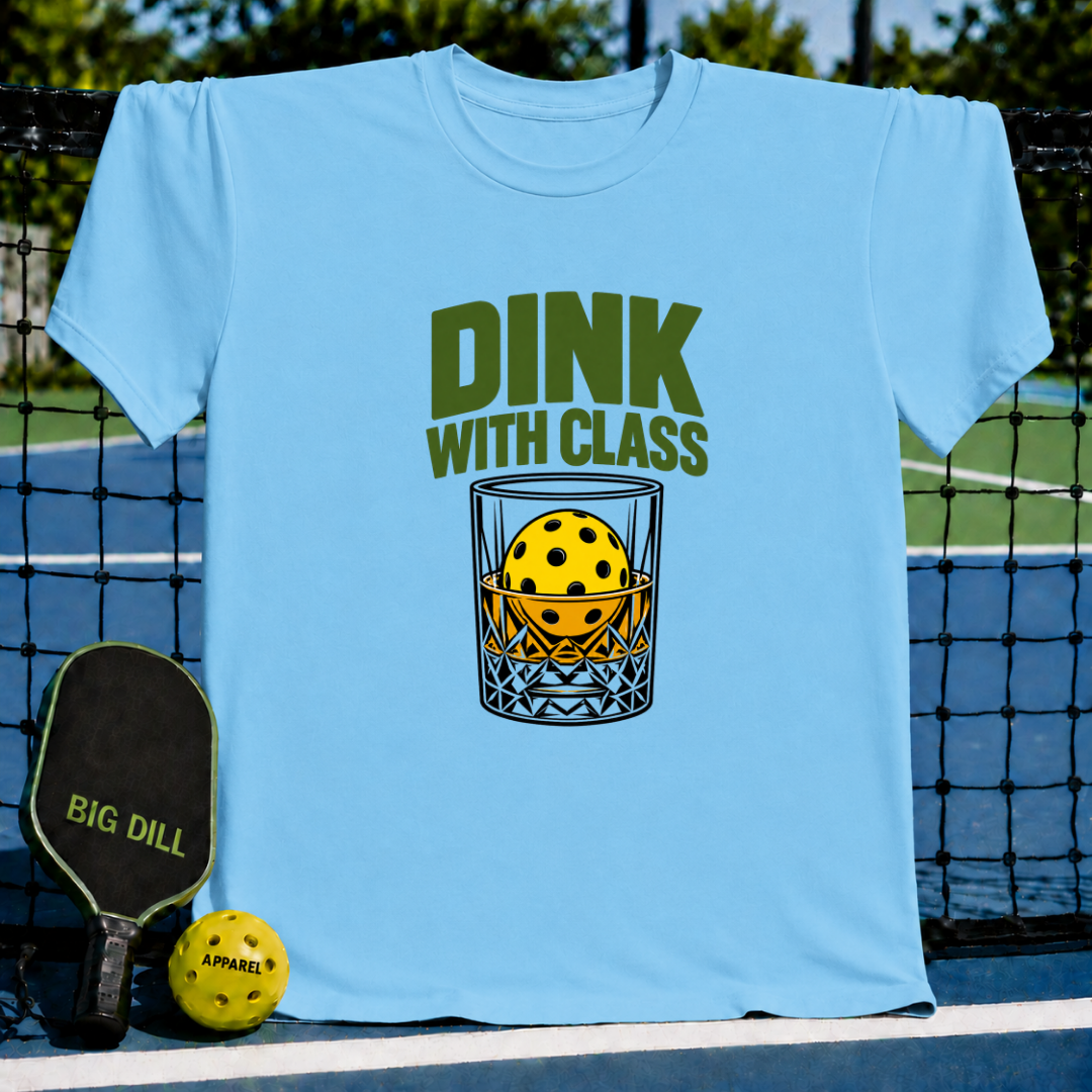 Light blue crew neck t-shirt featuring a Dink With Class graphic of a pickleball inside a whiskey glass on a court.