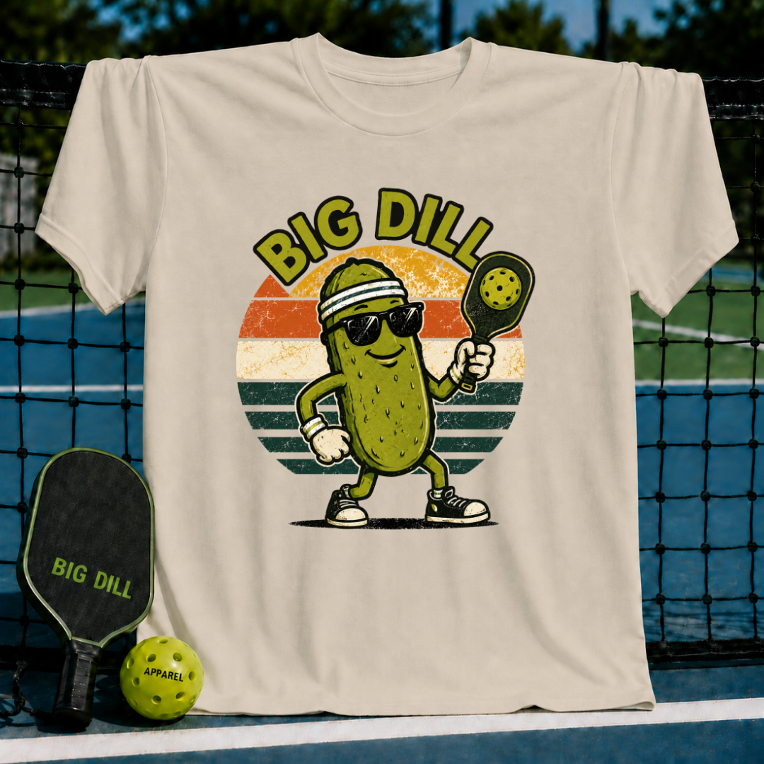 Beige unisex pickleball t-shirt featuring a retro sunset graphic of a cool pickle character with sunglasses and a paddle.