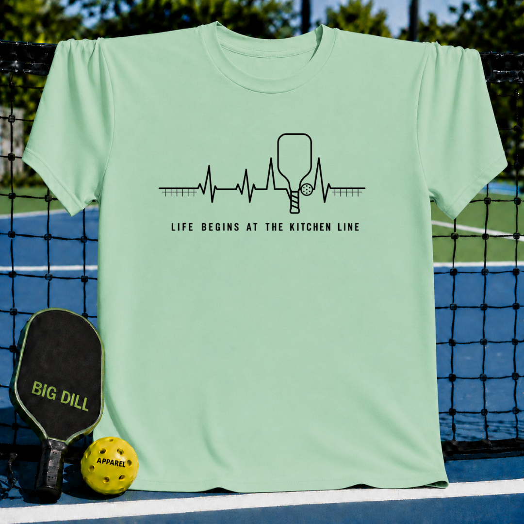 Light green pickleball t-shirt with a heartbeat graphic, paddle icon, and Life Begins At The Kitchen Line text.