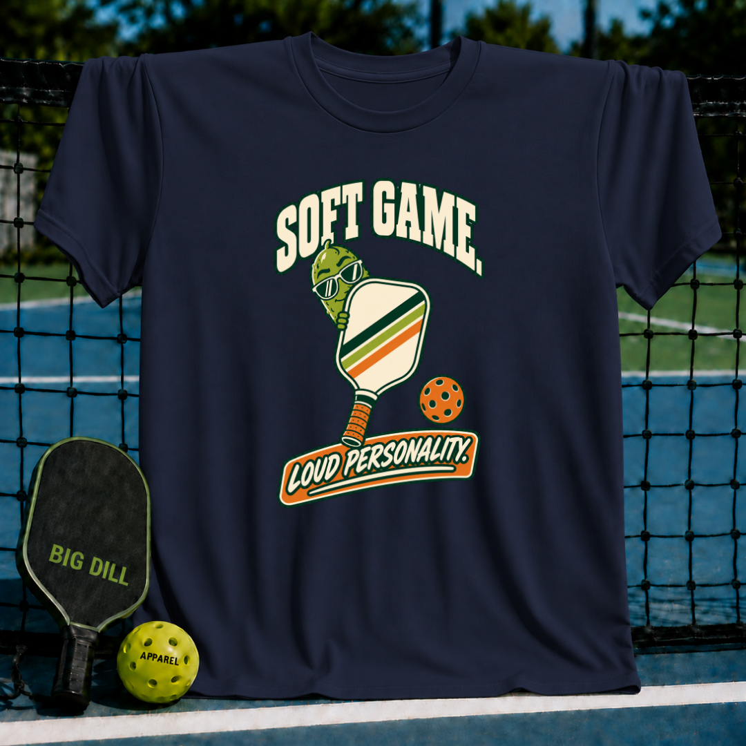 Navy blue crewneck t-shirt featuring a pickleball-themed graphic with a cartoon pickle, paddle, and Soft Game text.