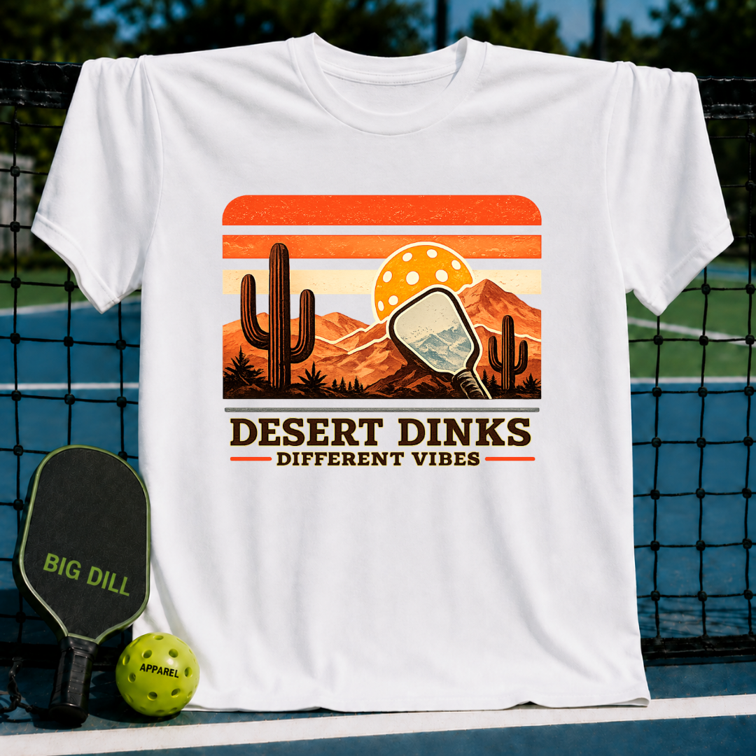 White crew neck t-shirt featuring a retro desert sunset graphic with a pickleball paddle, cacti, and Desert Dinks text.