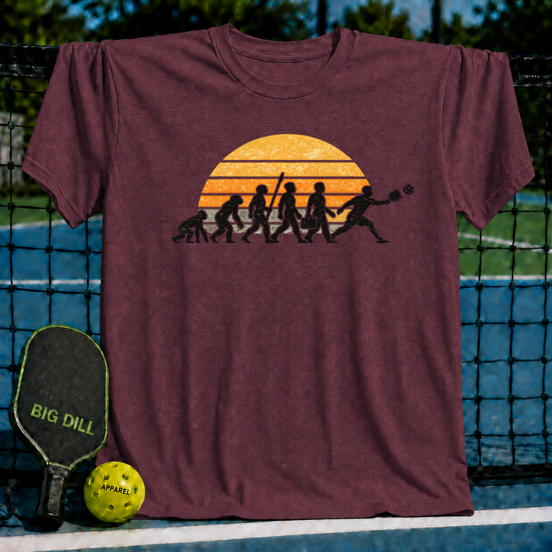 Maroon unisex t-shirt featuring a retro sunset evolution graphic of a man playing pickleball on a court.