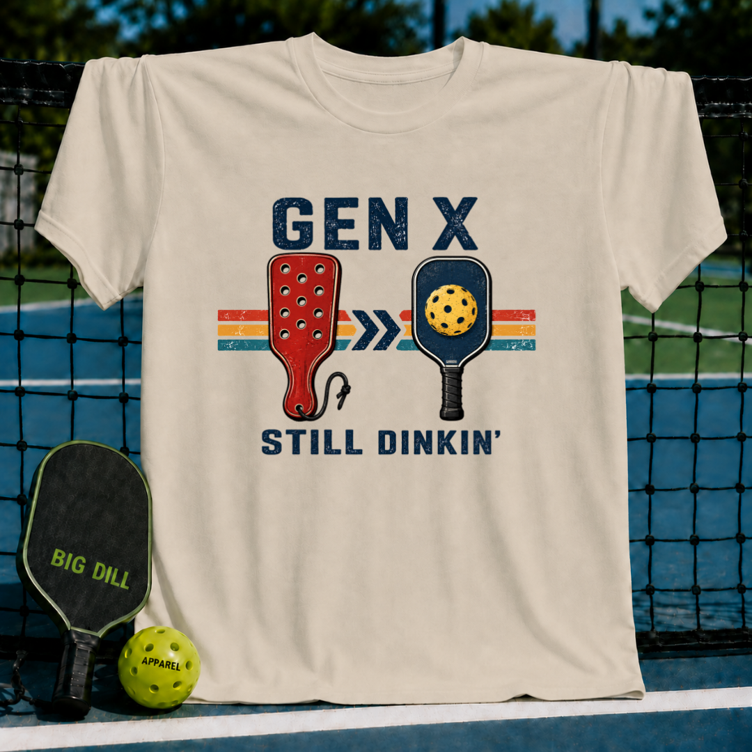 Cream-colored vintage-style t-shirt featuring a retro Gen X Still Dinkin' pickleball graphic on a pickleball court.