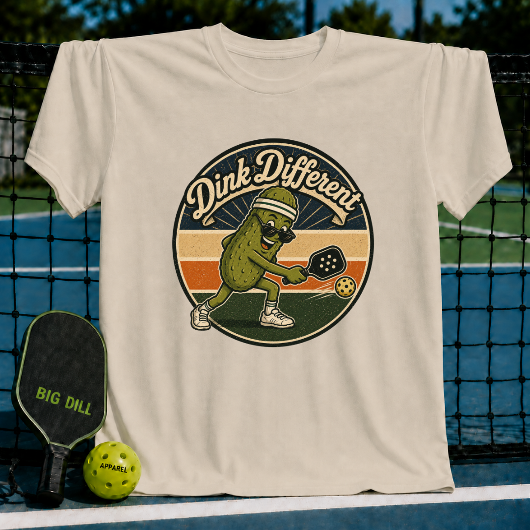 Heather gray unisex t-shirt featuring a retro pickleball-playing pickle graphic with the text Dink Different.