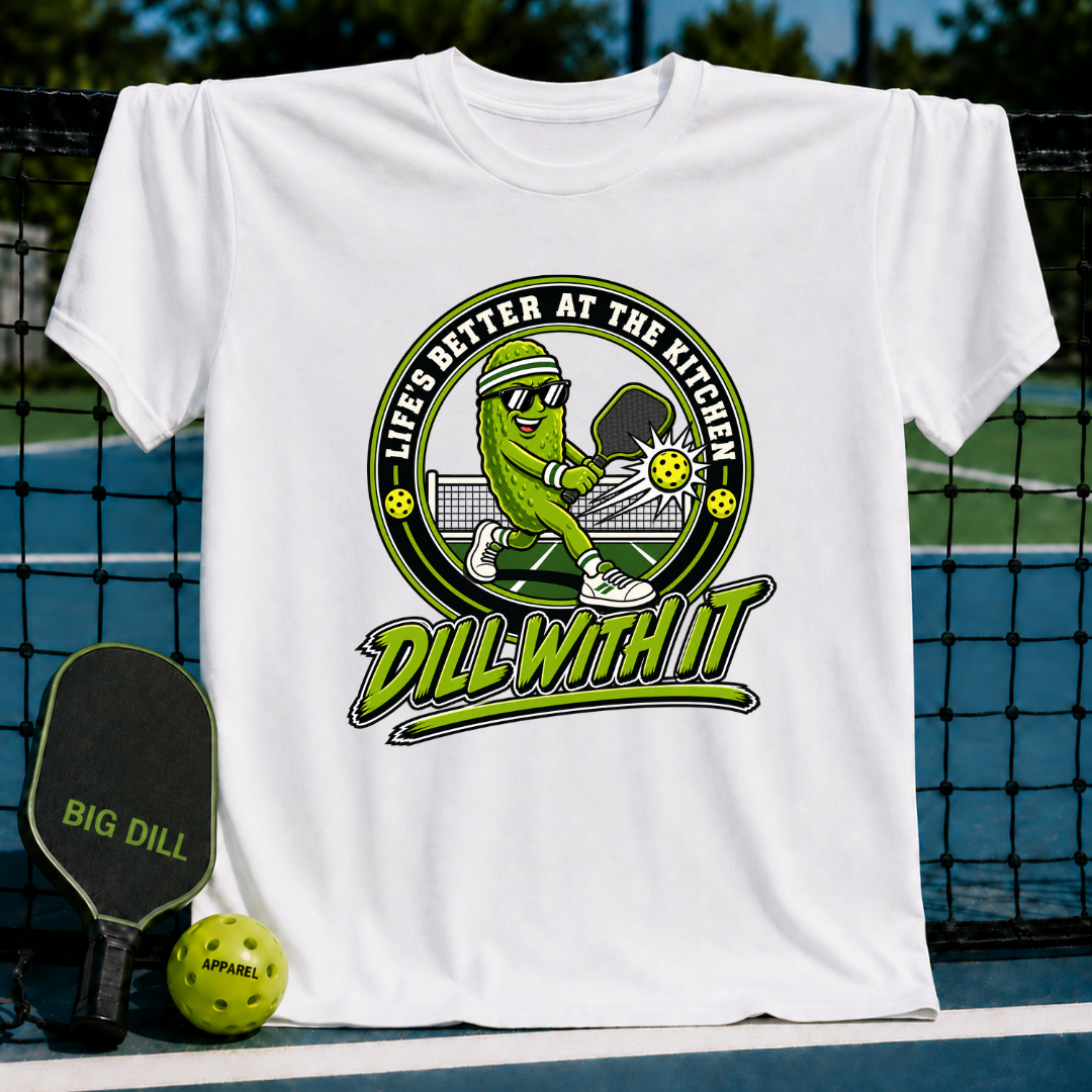 White cotton t-shirt featuring a cartoon pickle playing pickleball with the text Dill With It and Life's Better At The Kitchen.