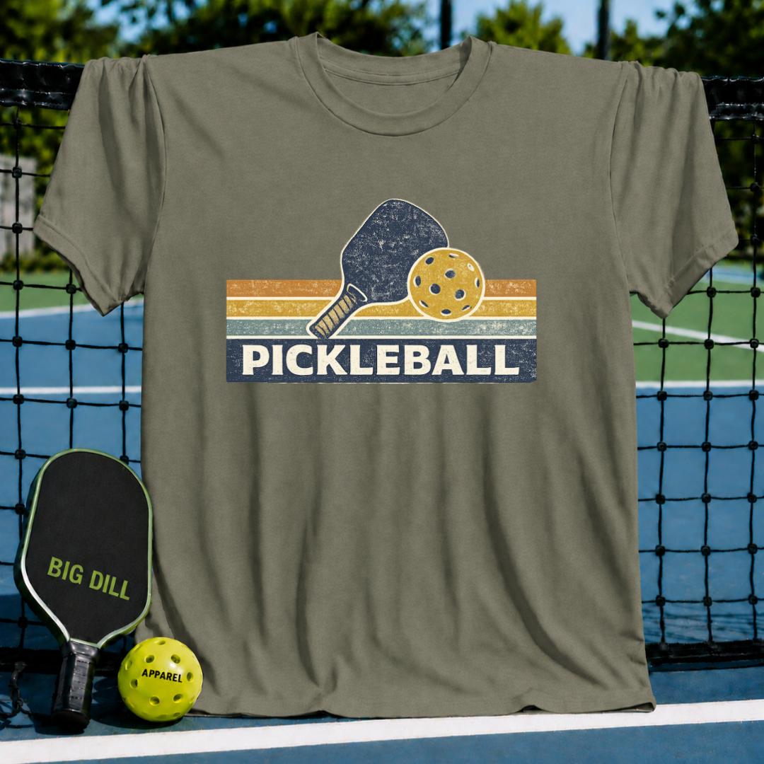 Olive green vintage-style cotton t-shirt featuring a retro striped graphic with a pickleball paddle and ball.