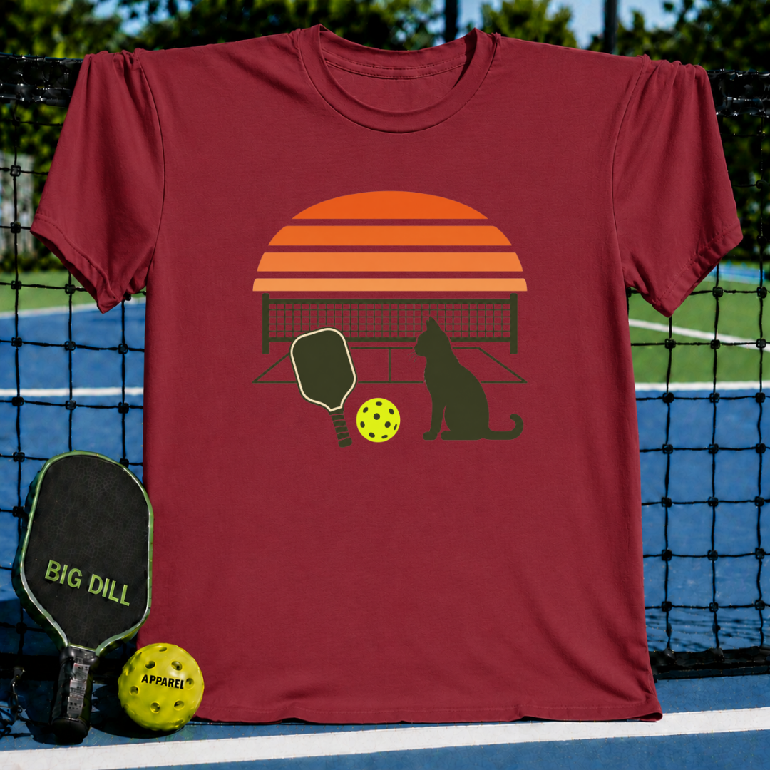 Maroon unisex t-shirt featuring a retro sunset, pickleball court, paddle, and cat silhouette graphic.