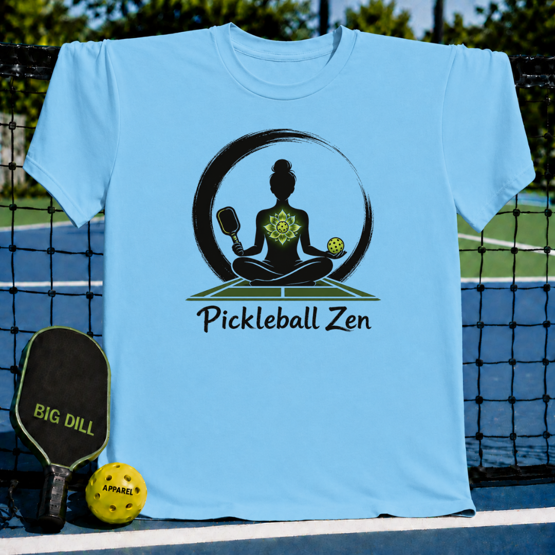 Light blue t-shirt featuring a Zen-inspired graphic of a woman meditating with a pickleball paddle and ball on a court.