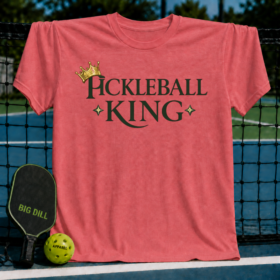 Vibrant coral unisex t-shirt featuring a gold crown and dark olive Pickleball King text with star accents on a court.