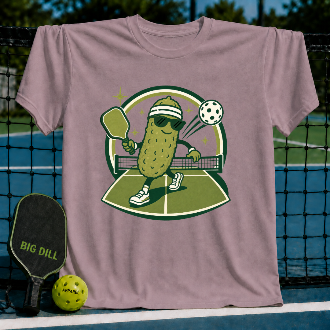 Mauve crewneck T-shirt featuring a cartoon pickle wearing sunglasses and a headband playing pickleball on a court.