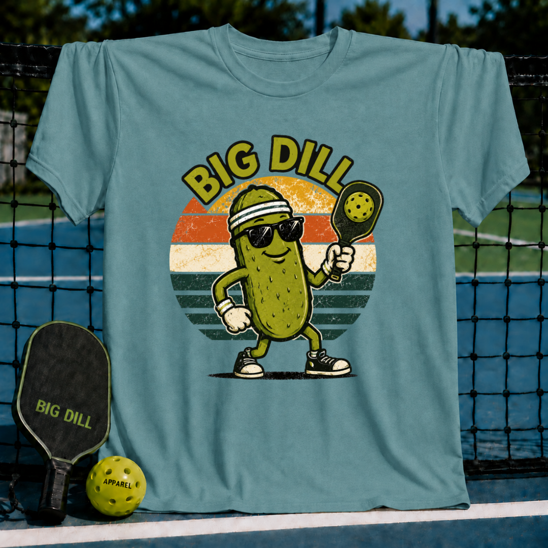 Blue-grey unisex pickleball t-shirt featuring a retro sunset graphic of a cool pickle character with sunglasses and a paddle.
